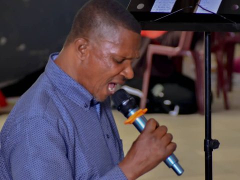 Un membre chante avec ferveur derrière le pupitre