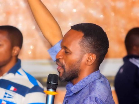 Un membre chante au micro tandis qu’un autre lève le bras