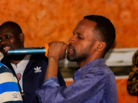 Un membre chante au micro, porté par l’assemblée